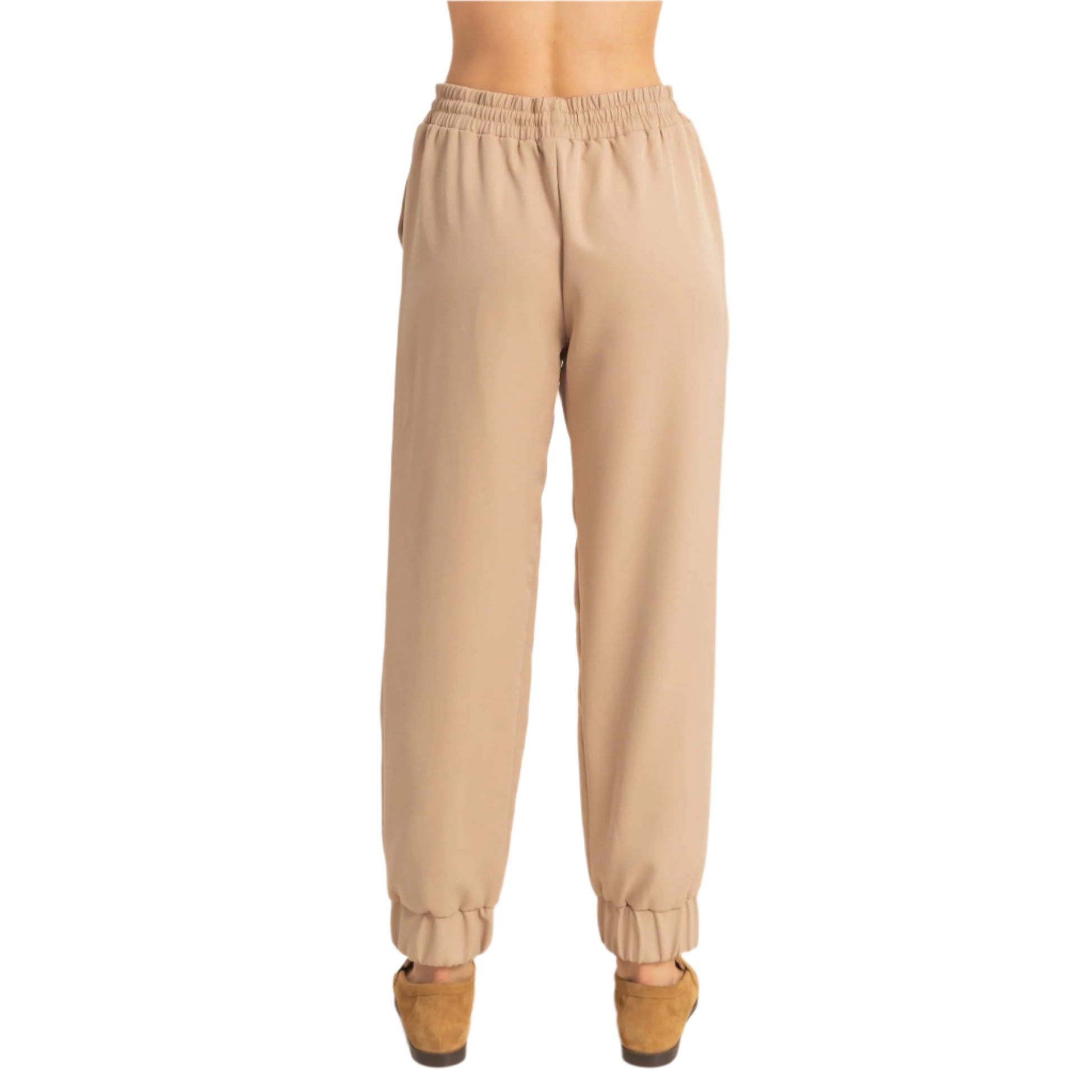 Beige jogger pants worn by a person on a beige background
