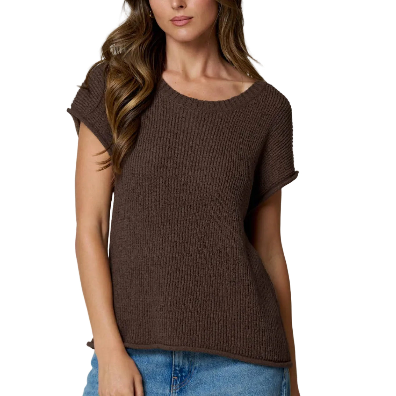 Woman wearing a brown knitted top and blue jeans on a light gray background