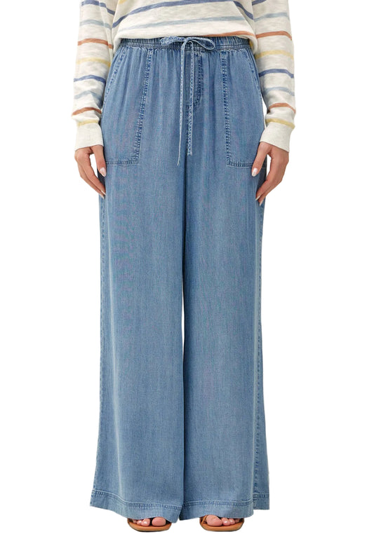 Person wearing blue wide-leg jeans and a striped long-sleeve shirt on a white background