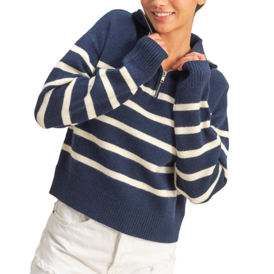 Woman wearing a navy and white striped sweater with a plain background