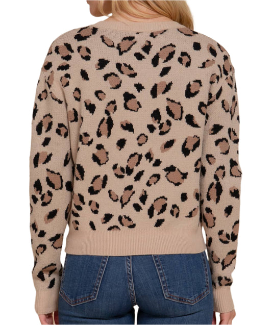 Woman wearing a beige sweater with a leopard print pattern on a beige background