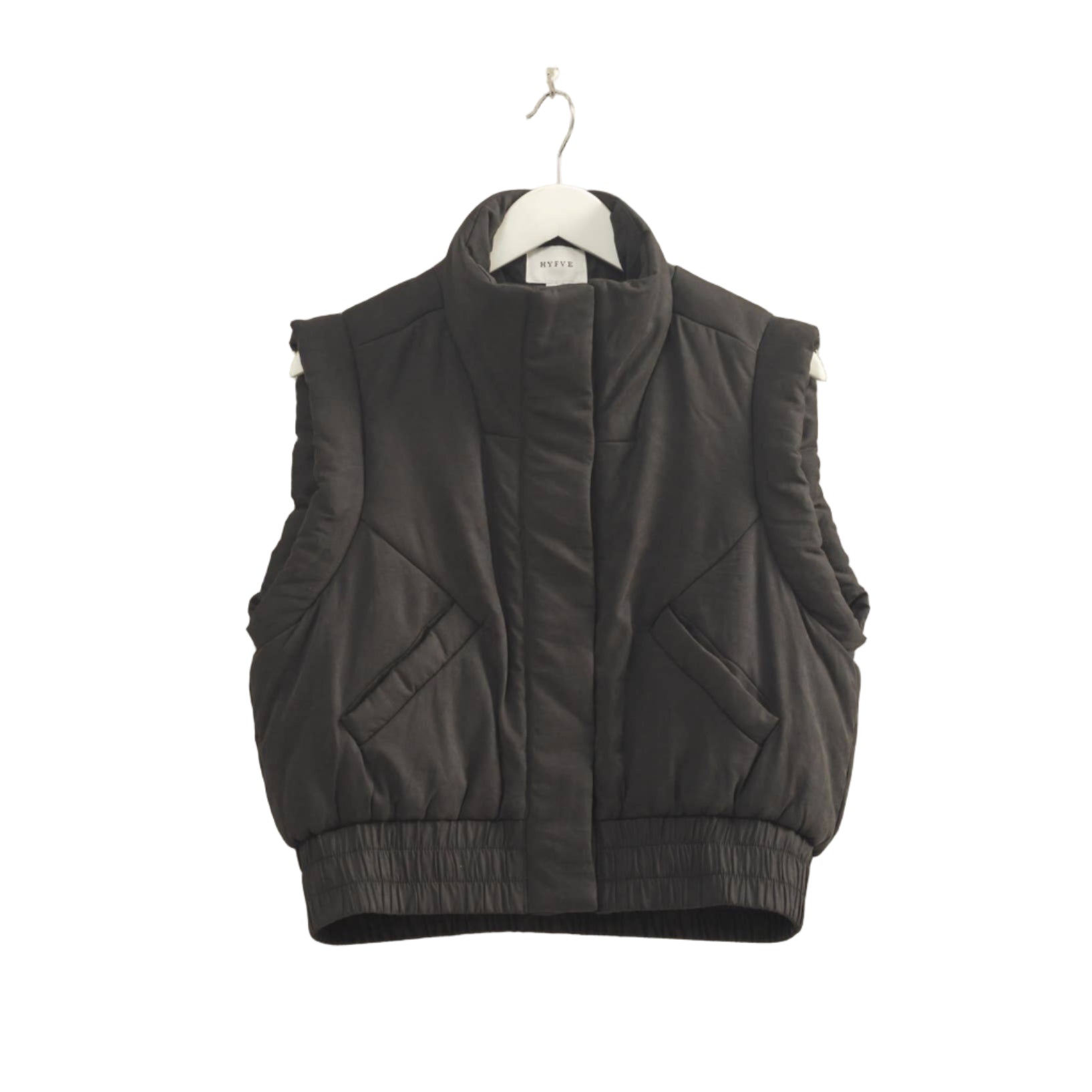 Black puffer vest on a hanger against a beige wall