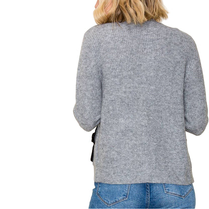 Person wearing a gray sweater and blue jeans against a white background
