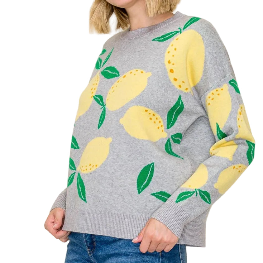 Person wearing a gray sweater with lemon patterns on a plain background