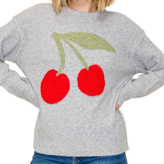 Woman wearing a gray sweater with red cherries and green leaves on a beige background