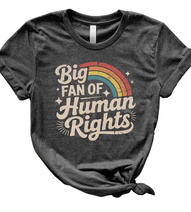 Black t-shirt with 'Big Fan of Human Rights' text and rainbow design on a wooden surface.