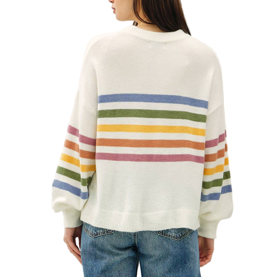 Person wearing a white sweater with rainbow stripes and blue jeans on a white background