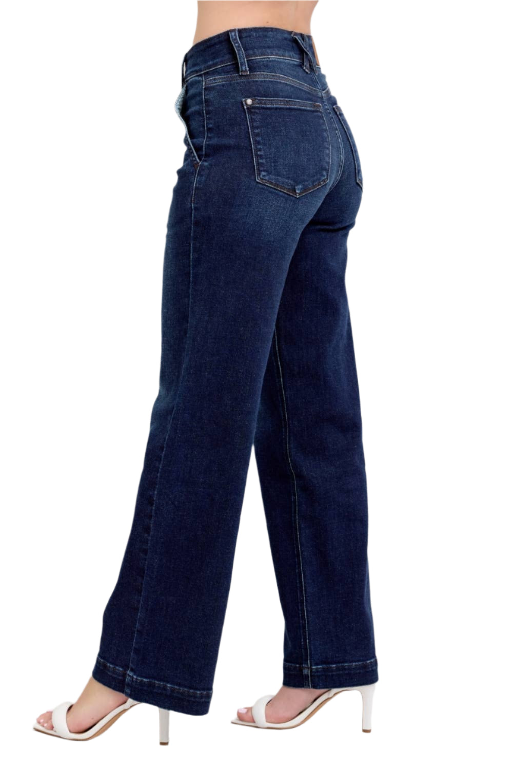 Dark blue jeans worn by a person on a plain background