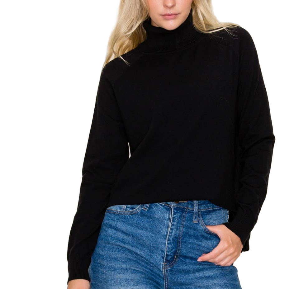 Person wearing a black turtleneck and blue jeans against a plain background