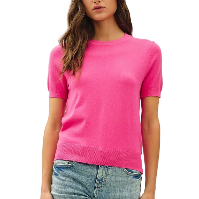 Woman wearing a bright pink t-shirt and light blue jeans on a white background