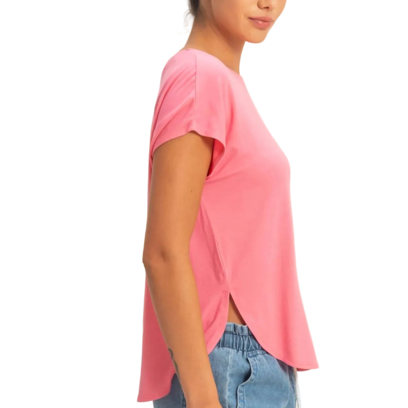 Woman wearing a pink t-shirt and blue jeans against a beige background