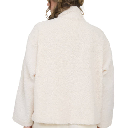 Person wearing a white coat with a Christmas tree in the background