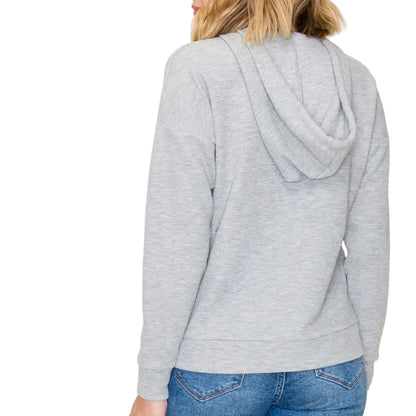 Person wearing a gray hoodie and blue jeans on a plain background