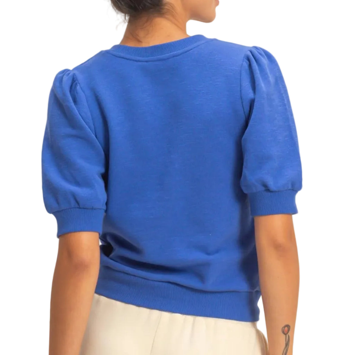 Person wearing a blue sweater with puffed sleeves against a beige background