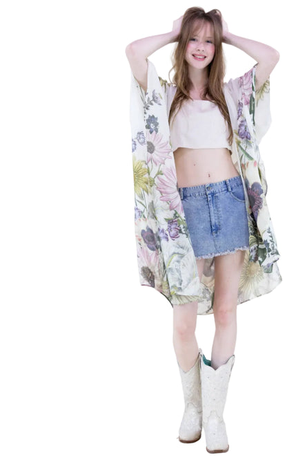 Woman wearing a floral kimono, white top, denim skirt, and white boots on a plain background