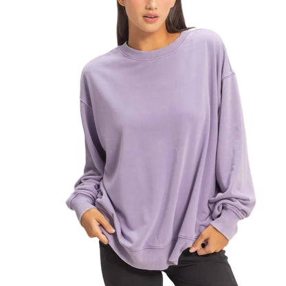 Woman wearing a purple oversized sweater and black shorts on a plain background