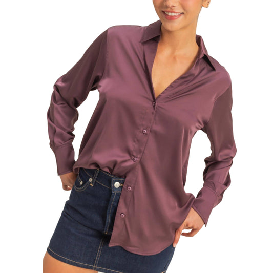 Woman wearing a long-sleeve purple shirt and denim skirt on a beige background