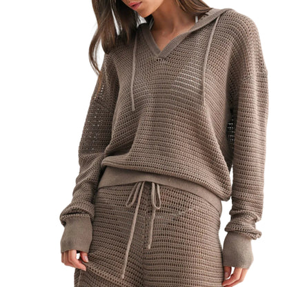 Woman wearing a brown knitted hoodie and pants on a light gray background