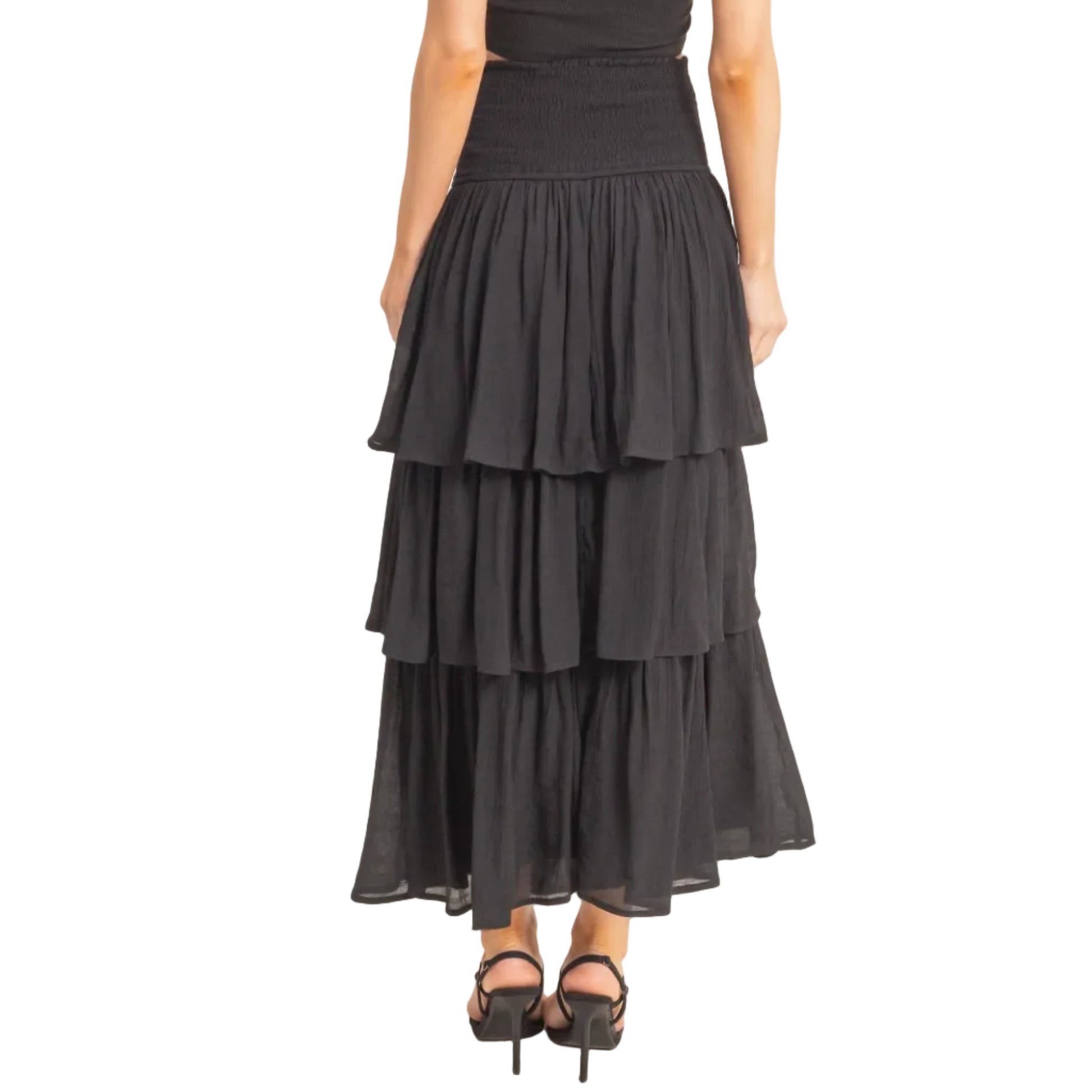 Black tiered skirt worn by a person on a plain background