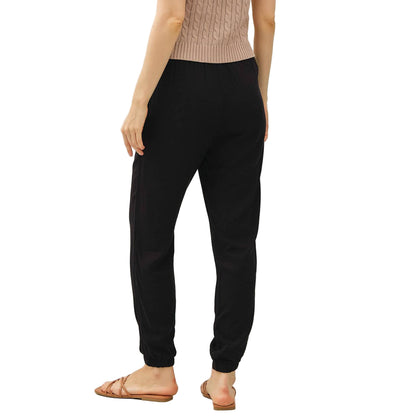 Woman wearing a beige sleeveless top and black pants on a white background