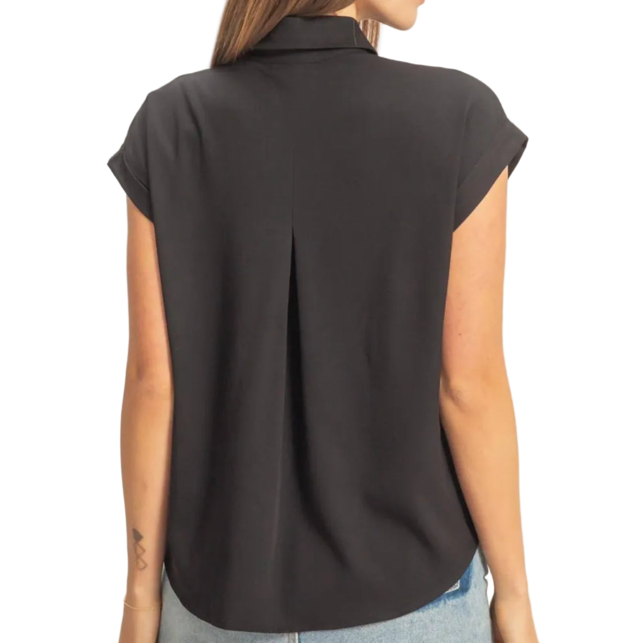 Woman wearing a black sleeveless blouse and denim skirt on a plain background