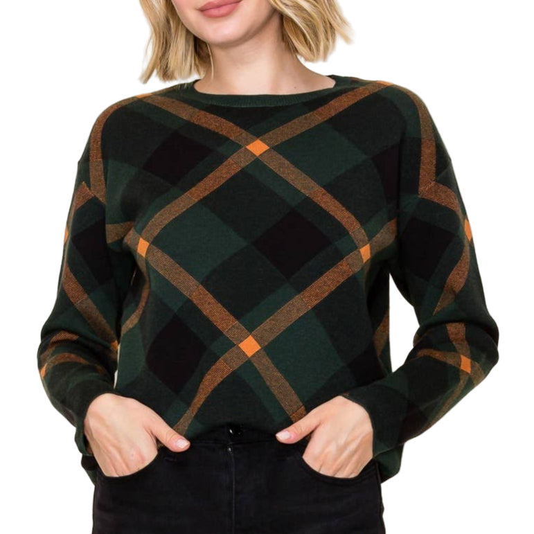 Woman wearing a green and brown plaid sweater against a plain background