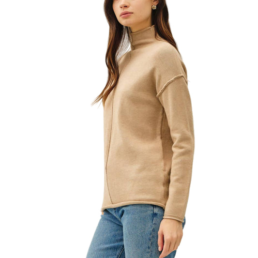 Woman wearing a beige sweater and blue jeans on a white background