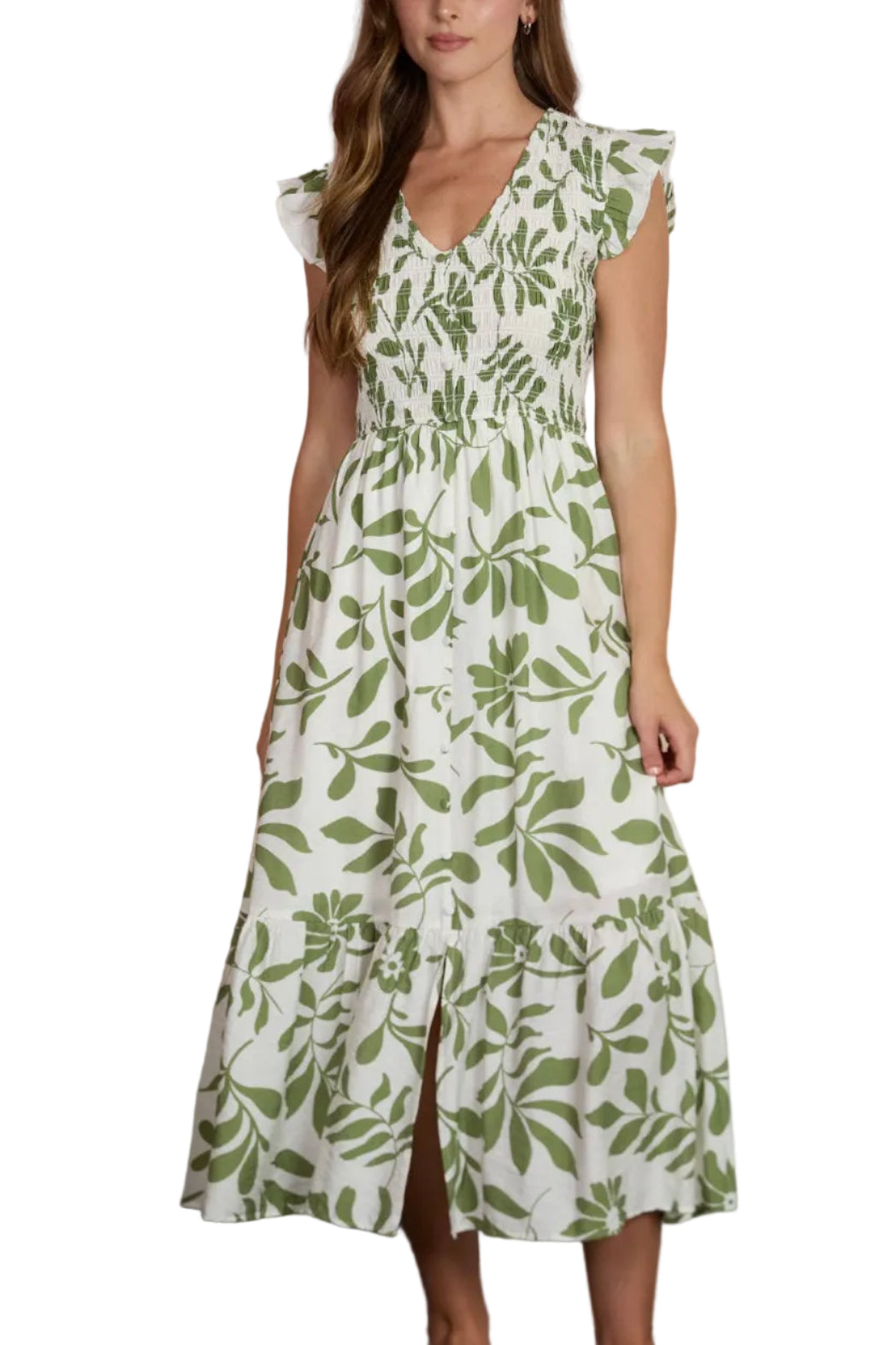 Woman wearing a green and white floral dress standing against a blurred outdoor background.