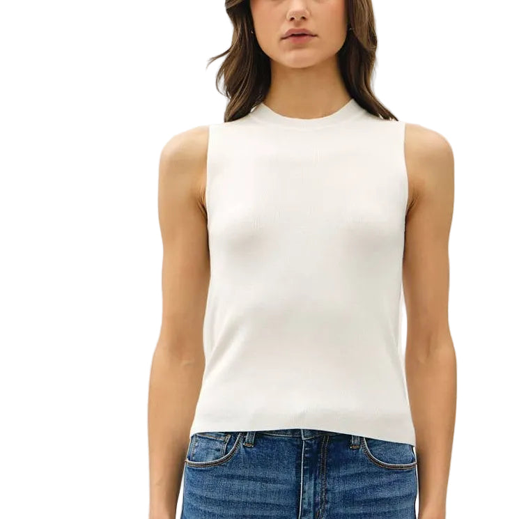 Woman wearing a white sleeveless top and blue jeans on a plain background