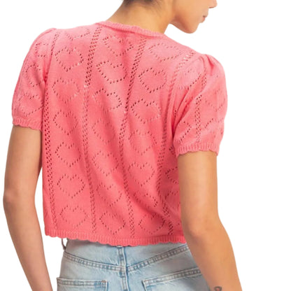 Person wearing a pink knitted top and light blue jeans on a plain background