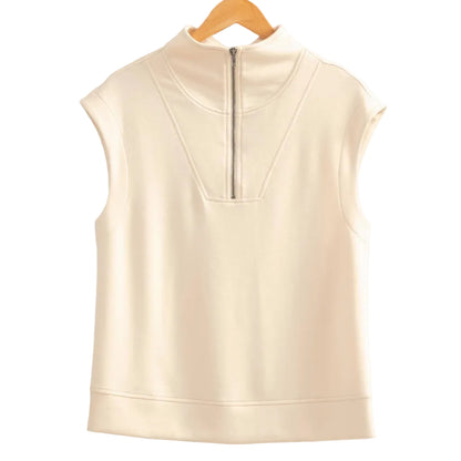 Beige sleeveless top on a wooden hanger against a beige wall