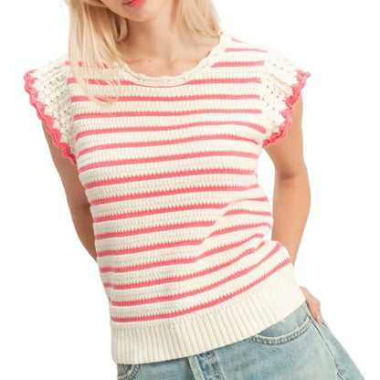 Woman wearing a pink and white striped sweater with lace sleeves on a plain background