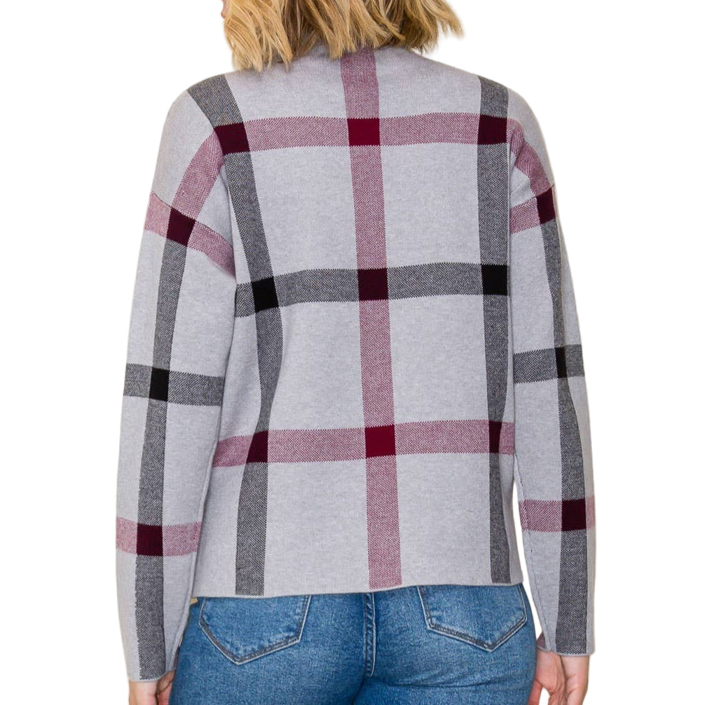 Person wearing a gray and red plaid cardigan with a plain background