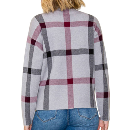 Person wearing a gray and red plaid cardigan with a plain background