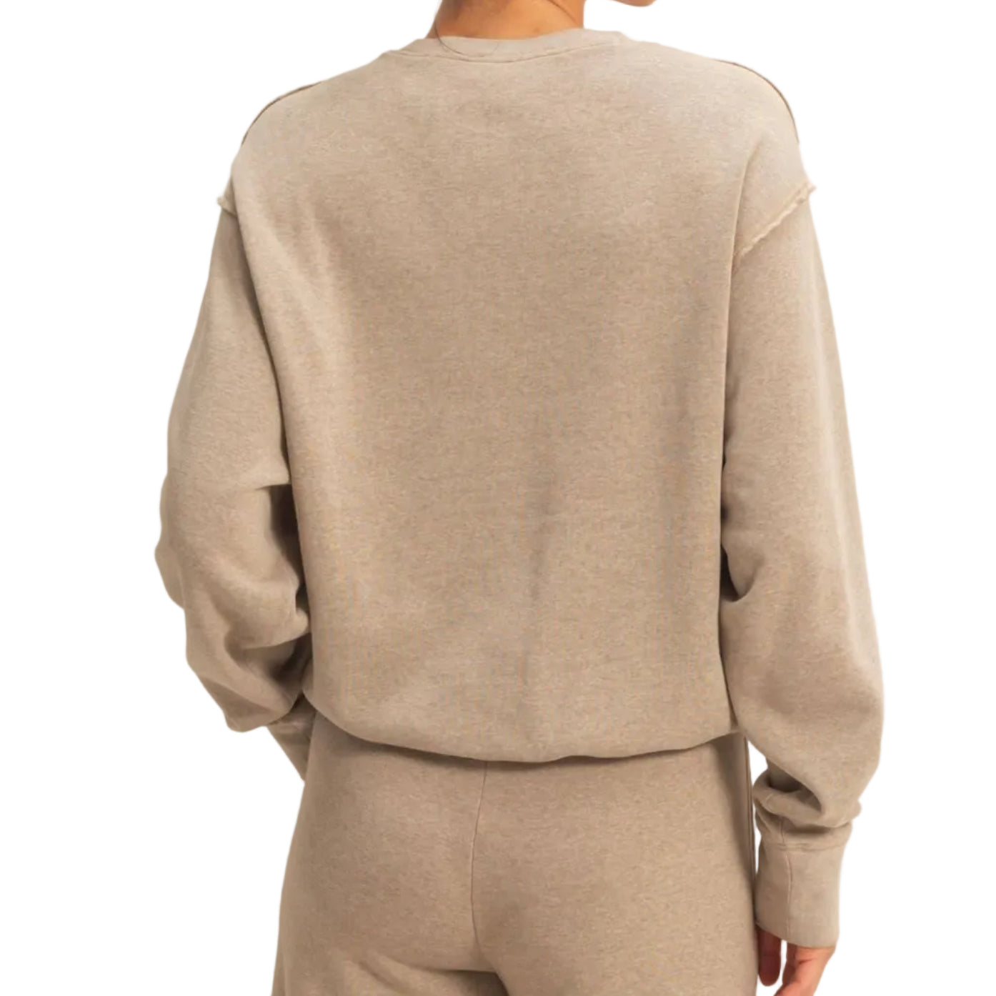 Person wearing a beige sweater and pants set on a plain background