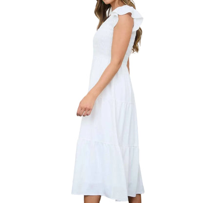 Woman in a white dress with red shoes standing in a room with produce and baskets.