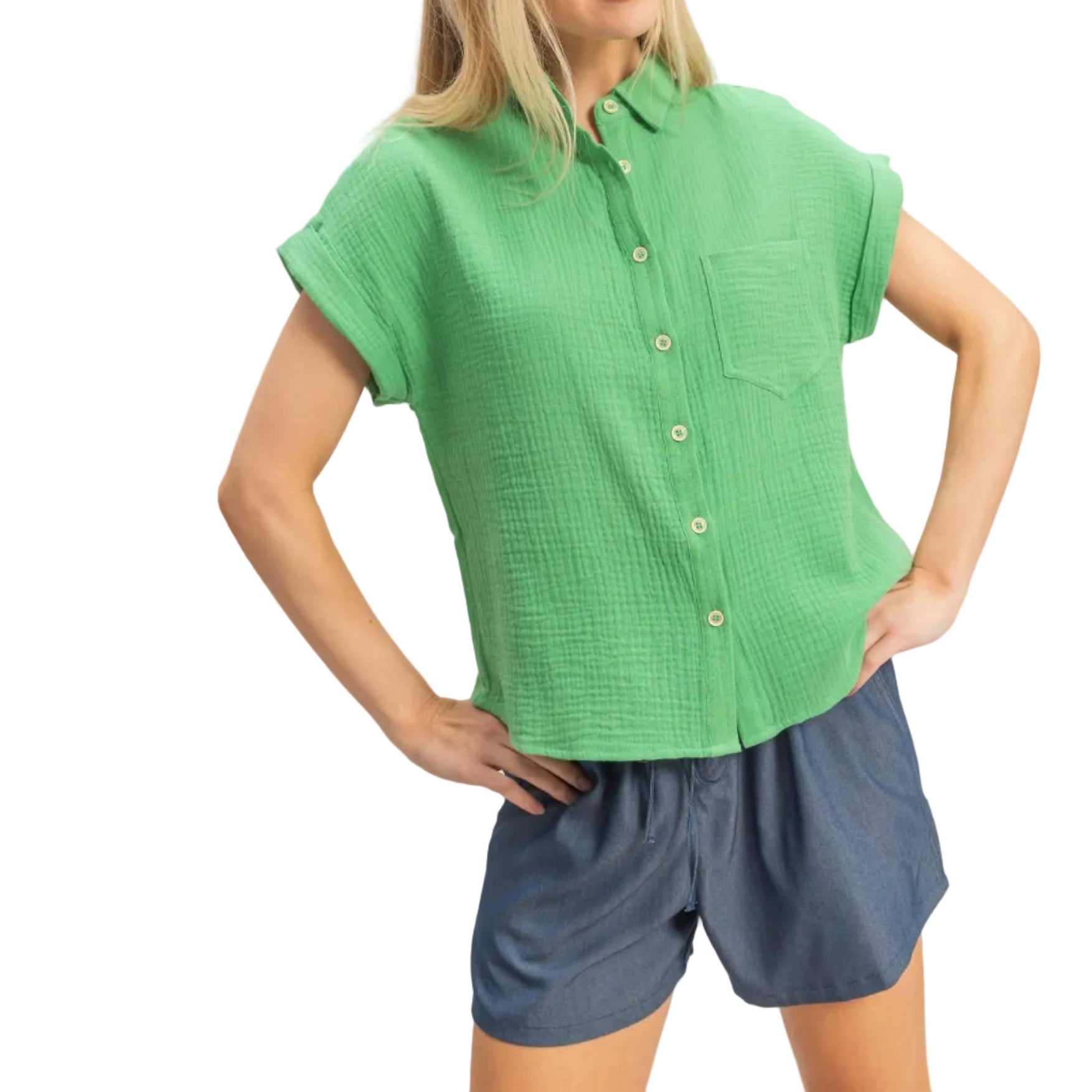 Woman wearing a green shirt and blue shorts on a plain background