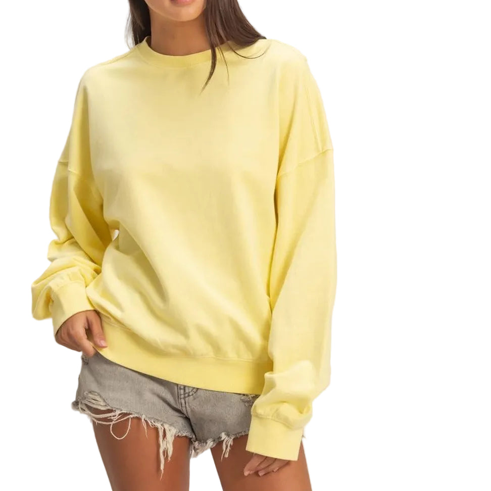 Woman wearing a yellow sweater and denim shorts on a plain background