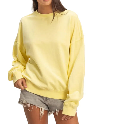 Woman wearing a yellow sweater and denim shorts on a plain background