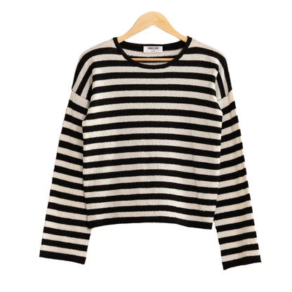Black and white striped sweater on a hanger against a plain background