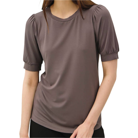 Woman wearing a brown blouse against a plain background