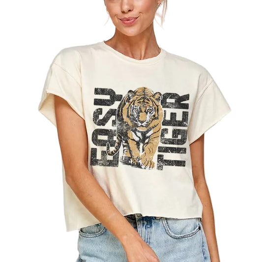 Woman wearing a cream t-shirt with a tiger graphic and text, standing against a plain background