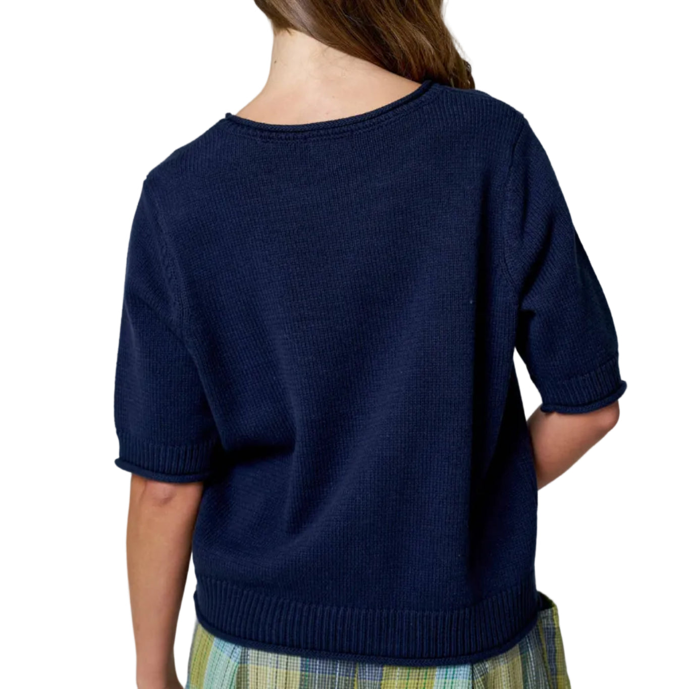 Person wearing a navy sweater and plaid skirt on a plain background