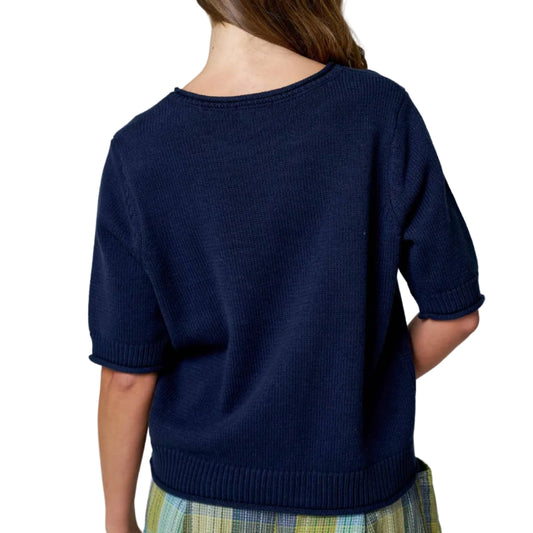 Person wearing a navy sweater and plaid skirt on a plain background
