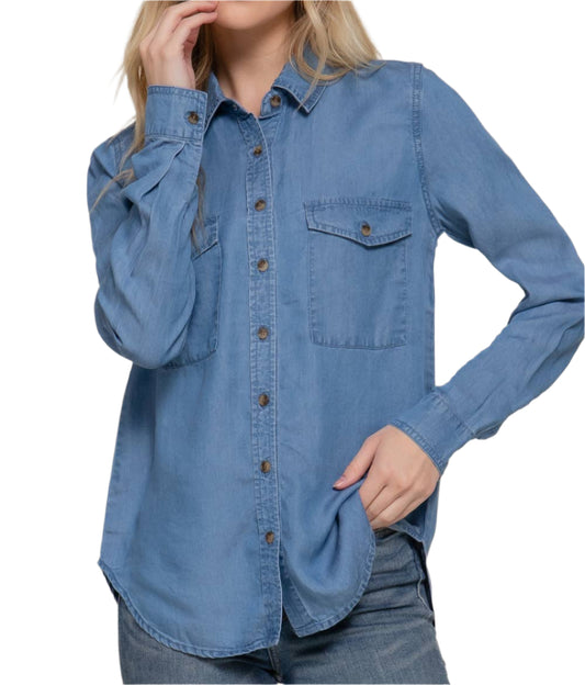 Woman wearing a blue denim shirt against a plain background