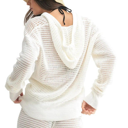 Person wearing a white crochet hoodie and shorts set with a straw hat on a white background