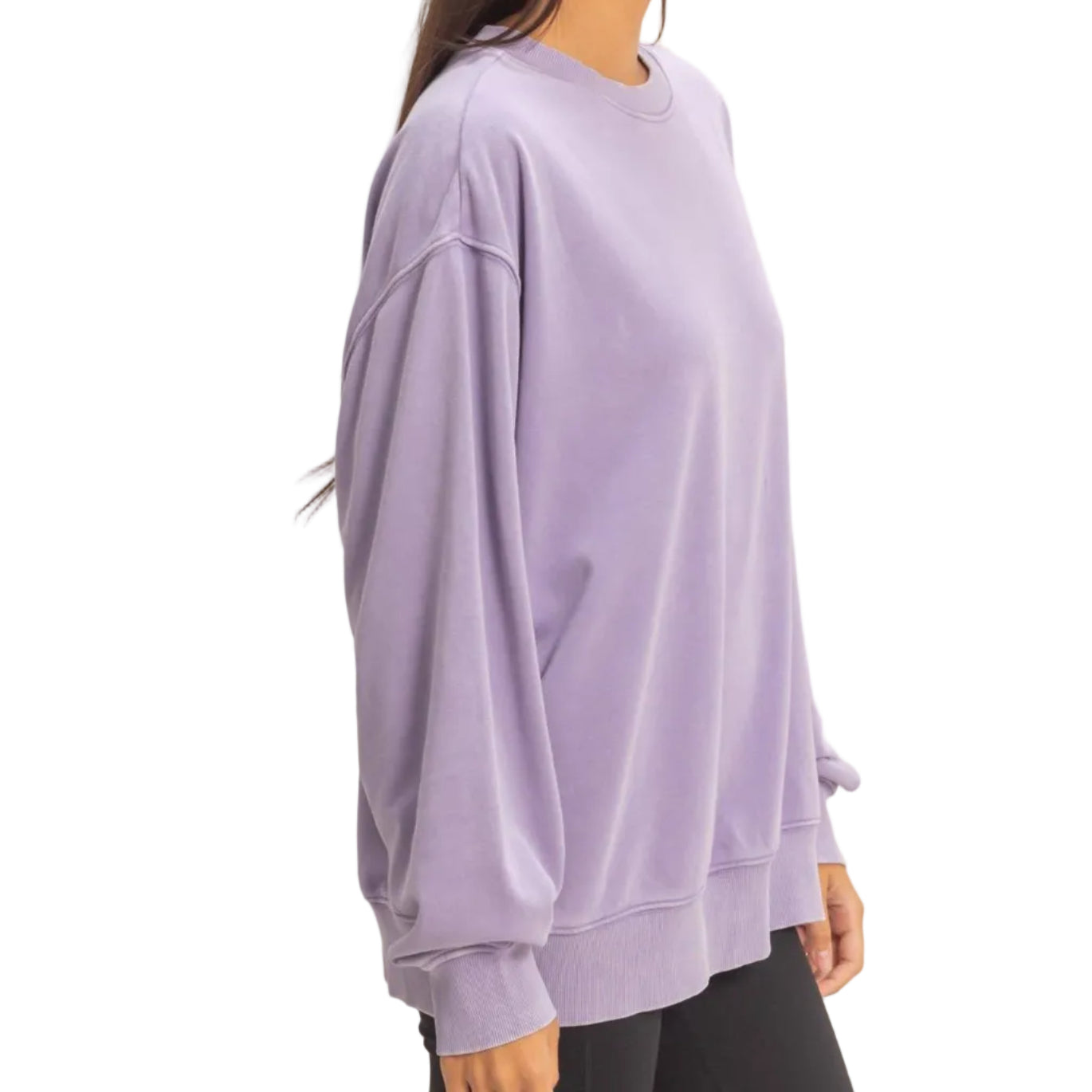 Woman wearing a light purple oversized sweatshirt and black shorts on a plain background