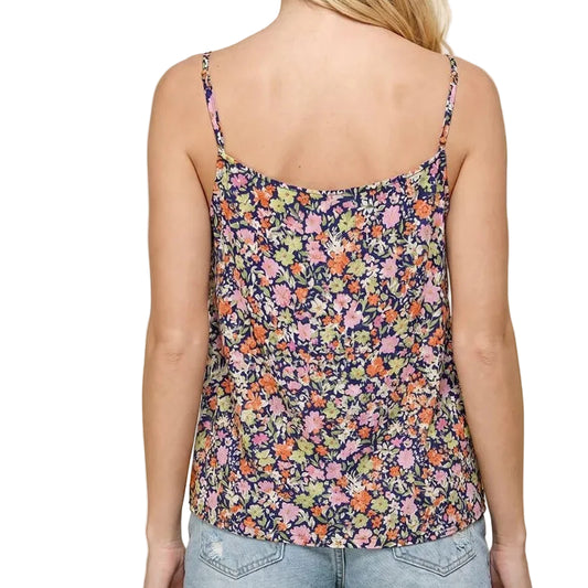 Woman wearing a floral tank top and denim shorts on a beige background