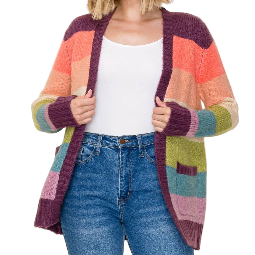 Woman wearing a colorful cardigan over a white top and blue jeans on a plain background