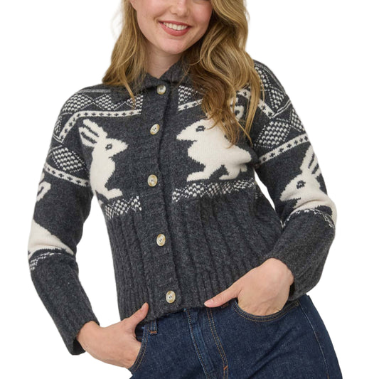 Woman wearing a patterned sweater with bunny designs on a plain background